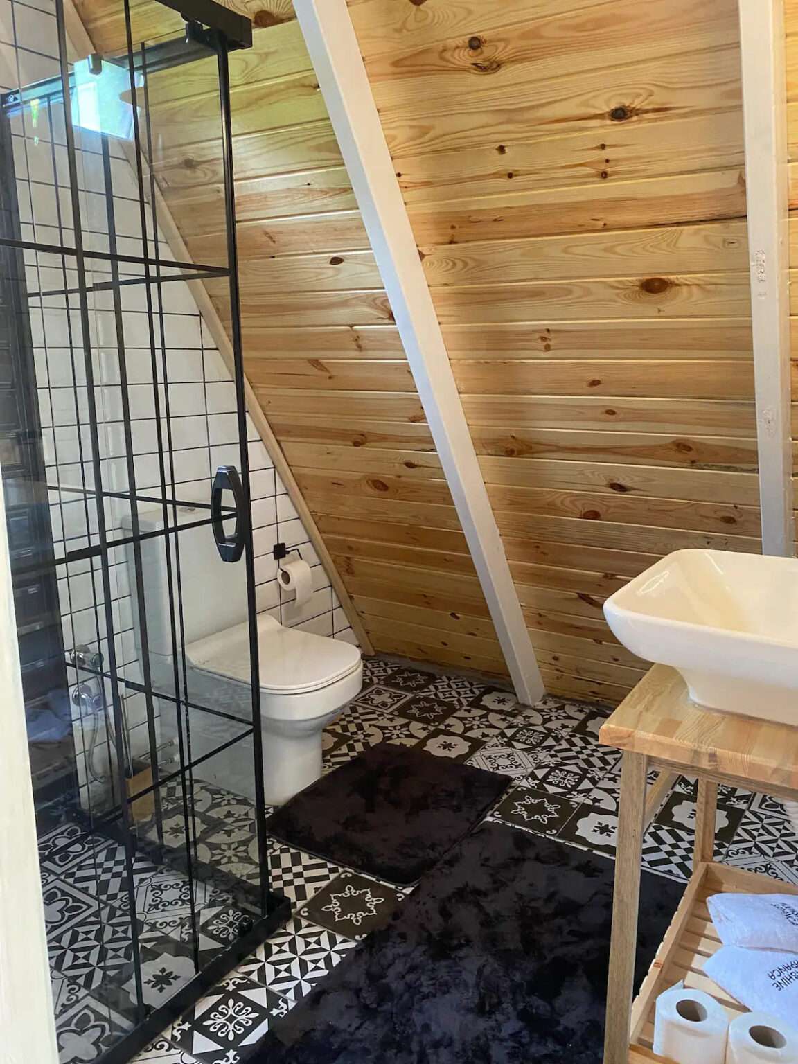 bathroom with a glass shower and black and white tiles