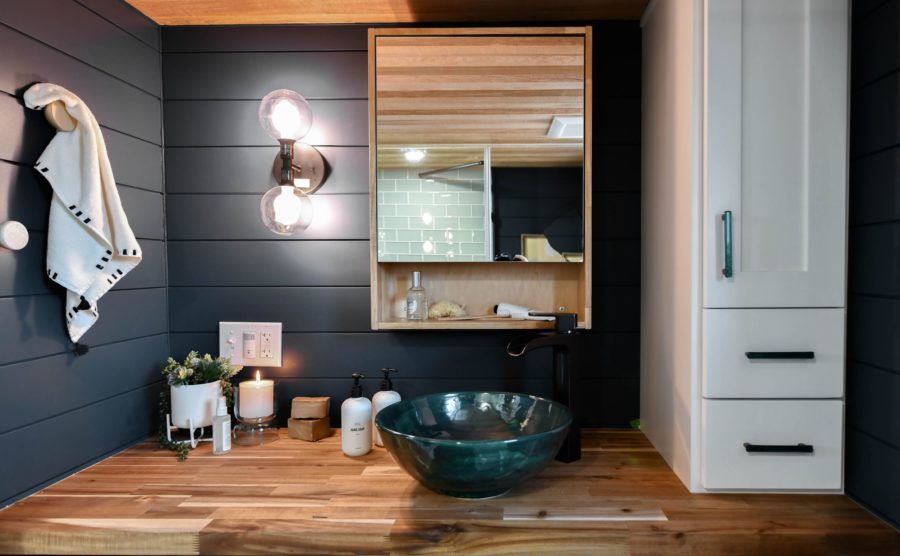 bathroom with dark walls, wooden countertop, dark green sink and a candle