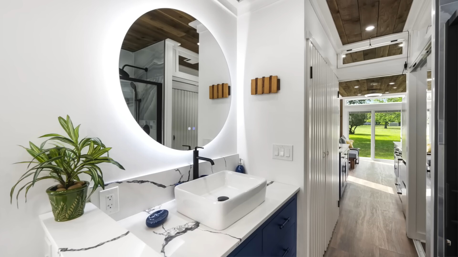 bathroom with a white sink, blue cabinets and a round mirror with white led lights