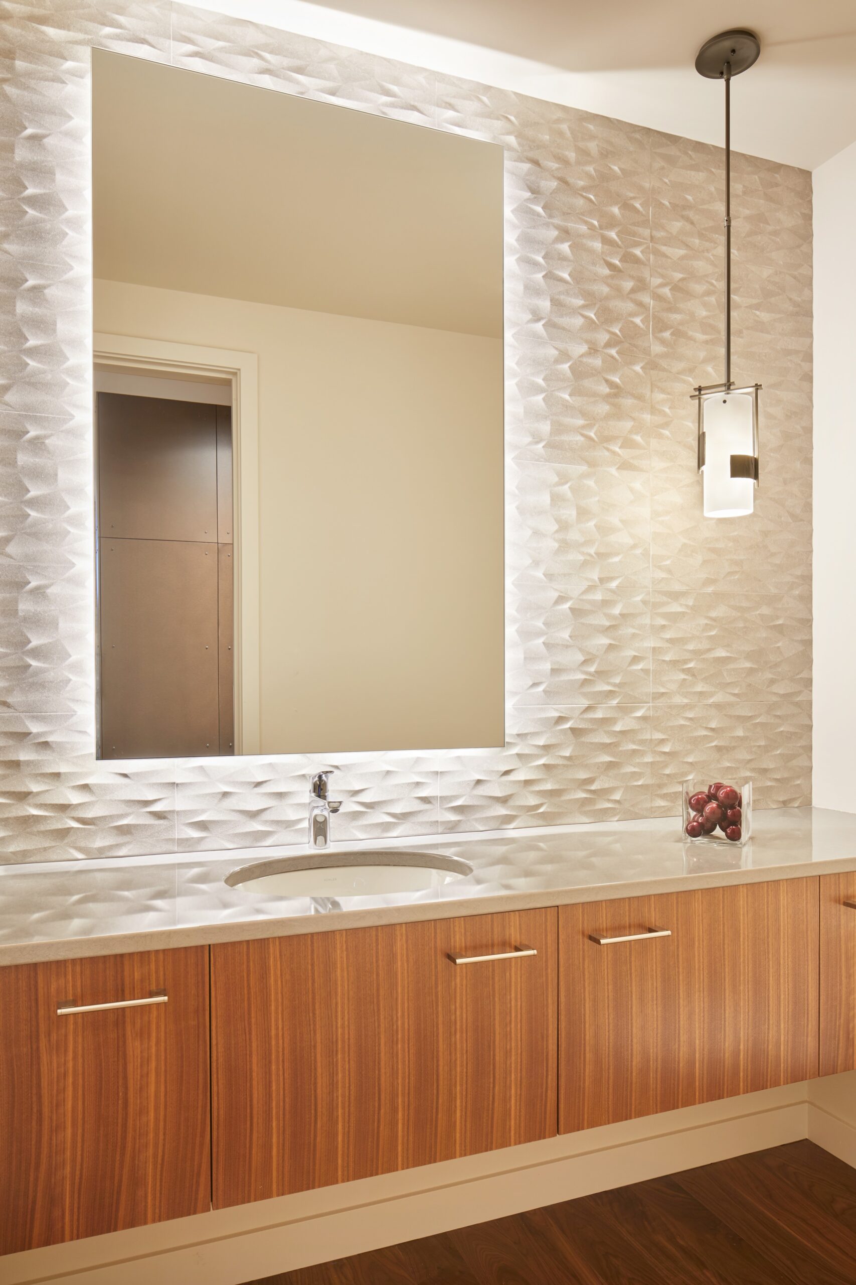 bathroom with brown cabinets, white countertop and a big mirror with led lights around it