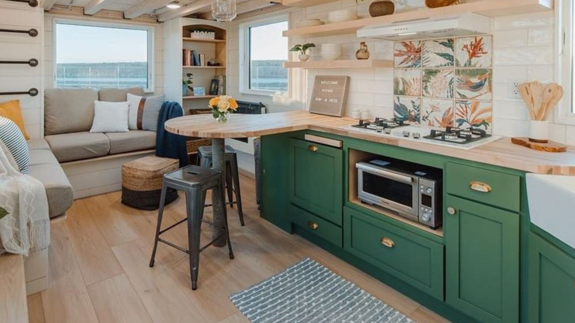 beautiful green kitchen cabinets with floating shelves on the wall and a round dining area