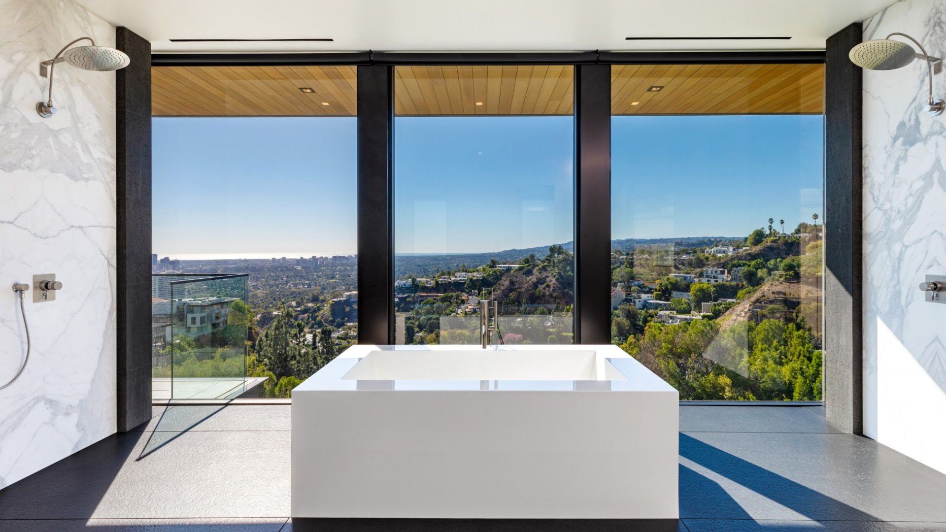 spacious bathroom with a big and beautiful suare tub, two rain showers, and a stunning view