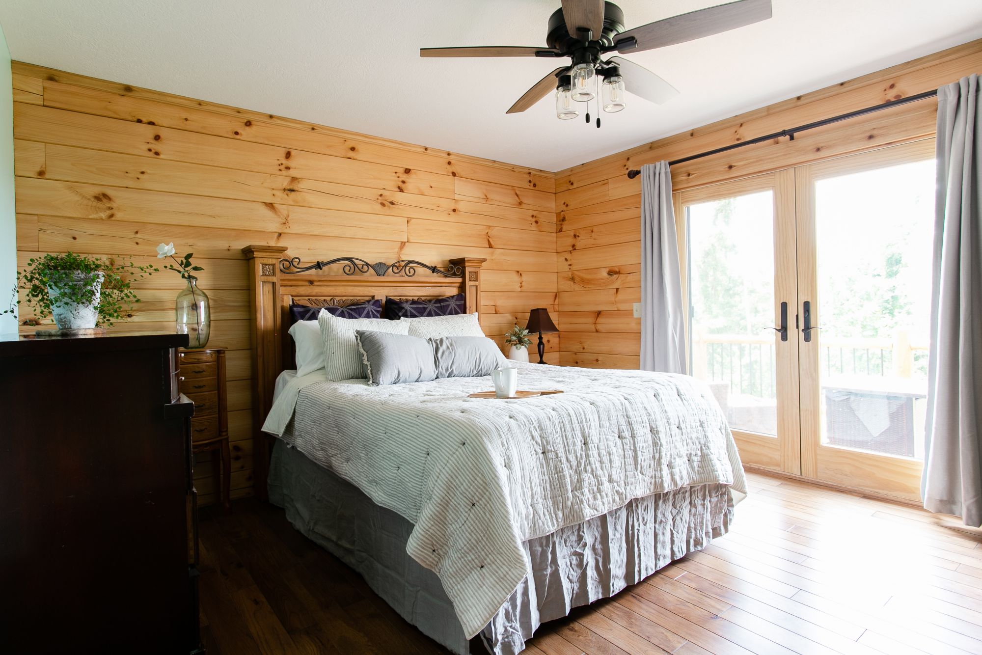 bedroom with a big comfy bed with white bed sheets and glass door which open up to a balcony