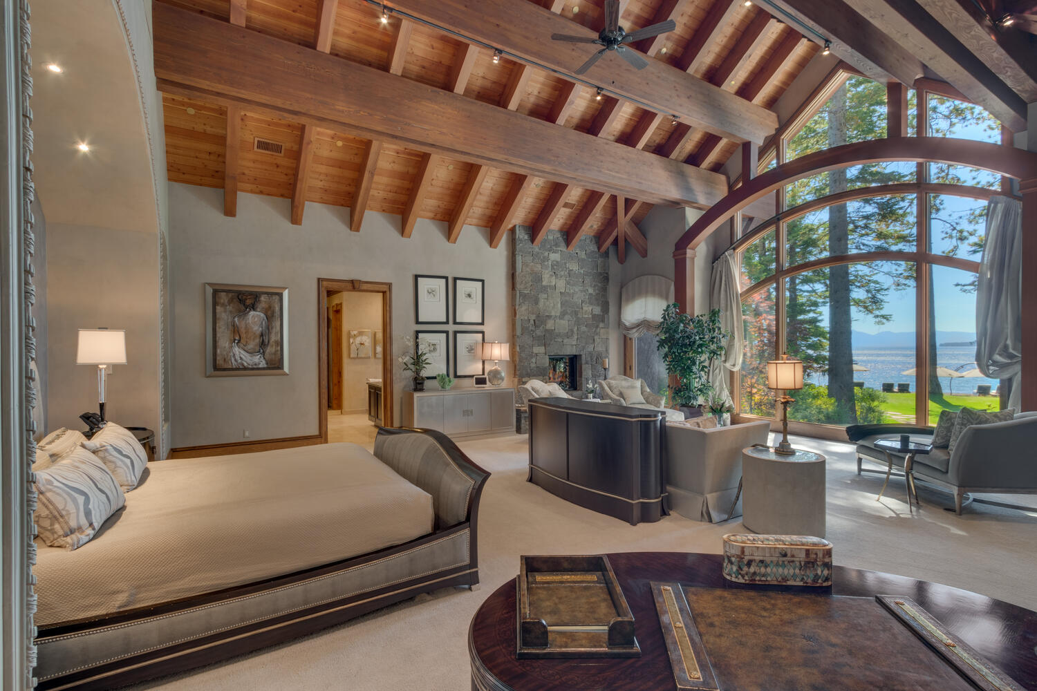 bedroom with floor to ceiling window, comfy bed in the middle and a sitting area next to the window