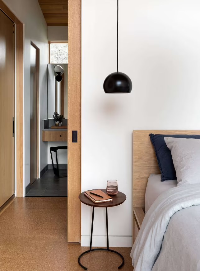 bedroom with a low hanging black lamp and a round bedside table