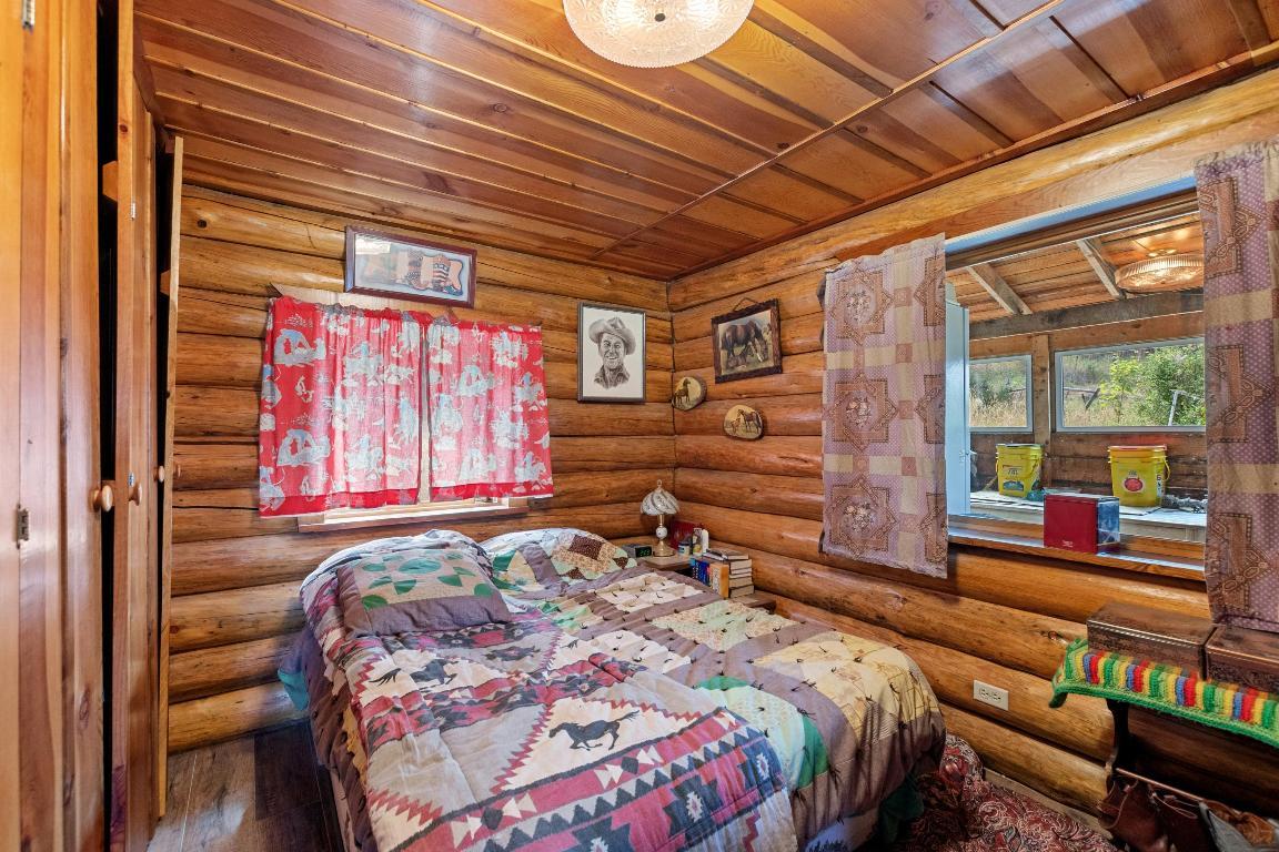 bedroom with wooden walls, wooden ceiling and wooden closet and textured bed sheets and textured curtains