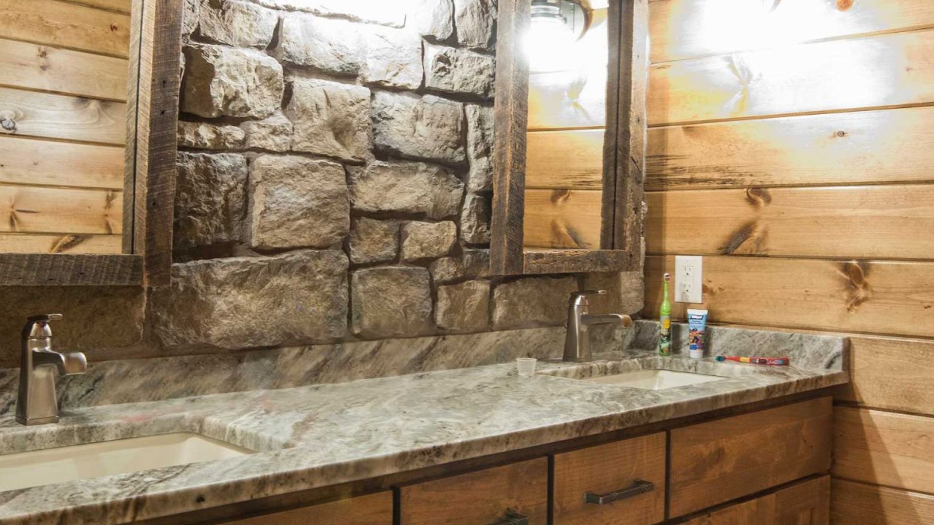 big bathroom vanity with lots of space, two sinks, two mirrors, and an accent stone wall