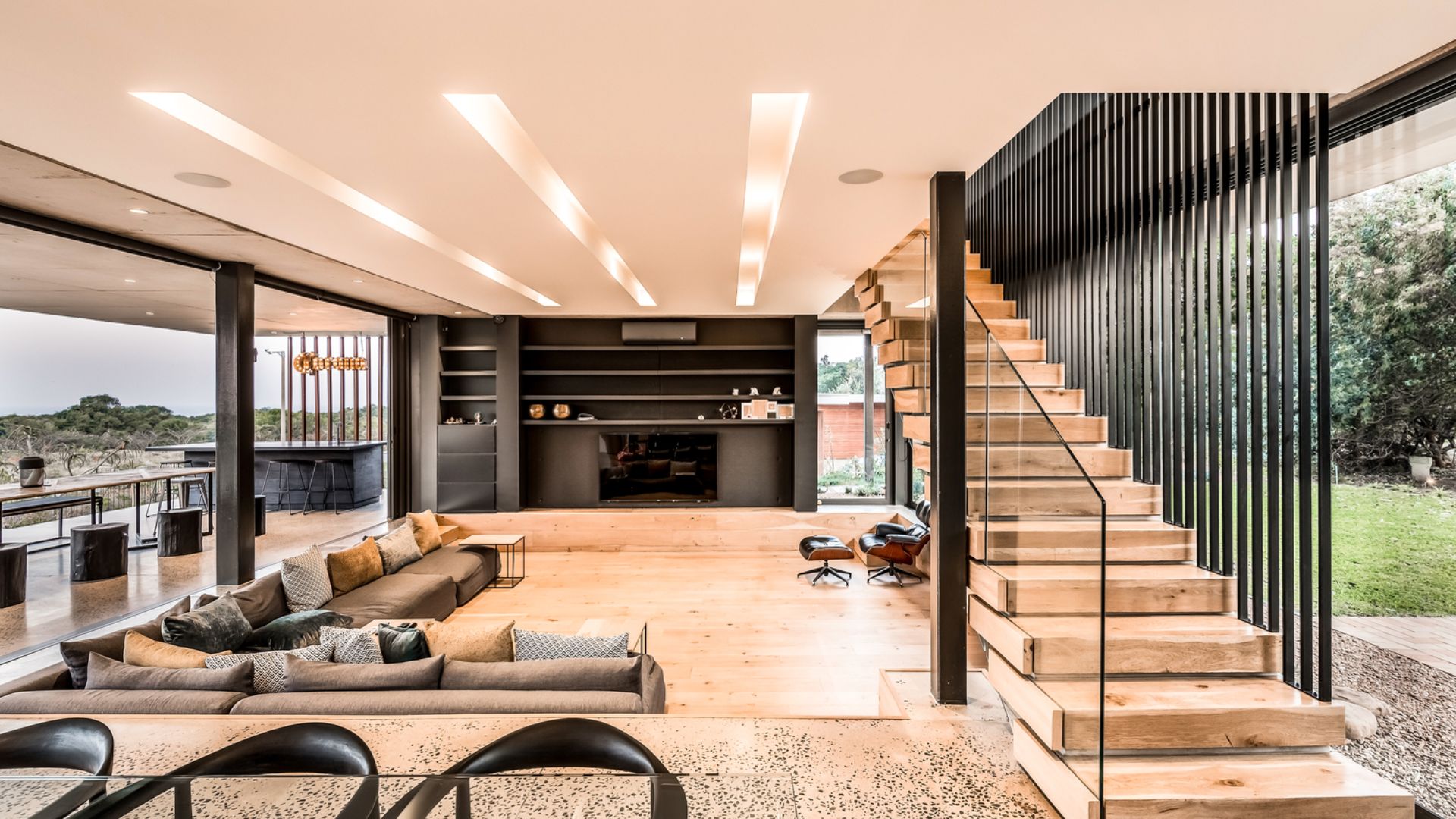 sunken living room with an L-shaped sofa, a leather armchair, and wooden stairs