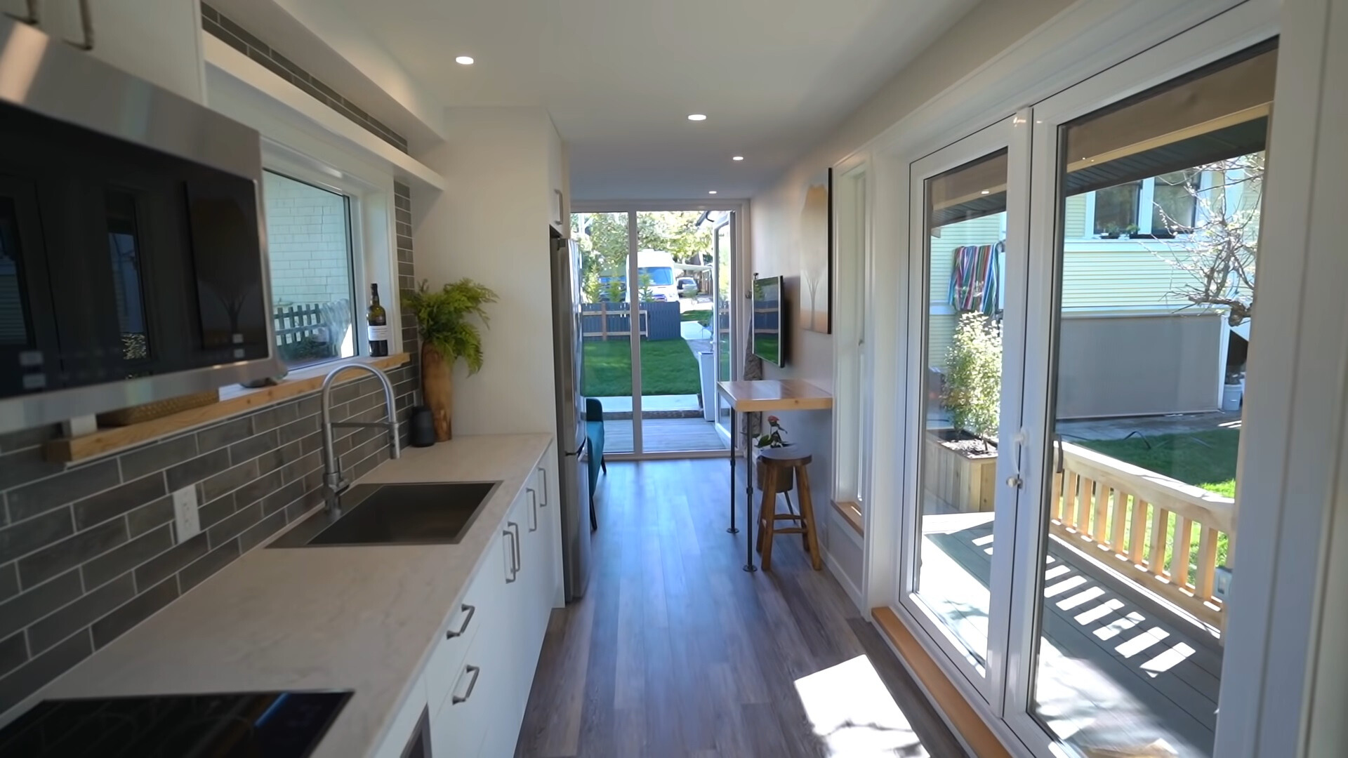 kitchen with white cabinets and glass doors and a big window, tiny brown table with a chair