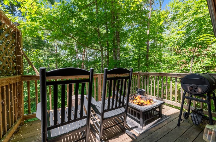 black chairs and a firepit outside the cabin with a view of the woods