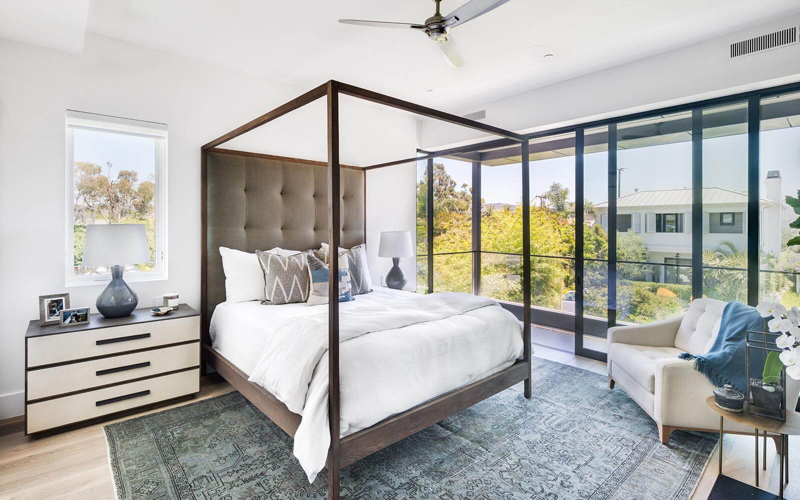 bedroom with a canopy bed, beautiful view on the balcony with glass doors and a cabinet and a chair in the corner