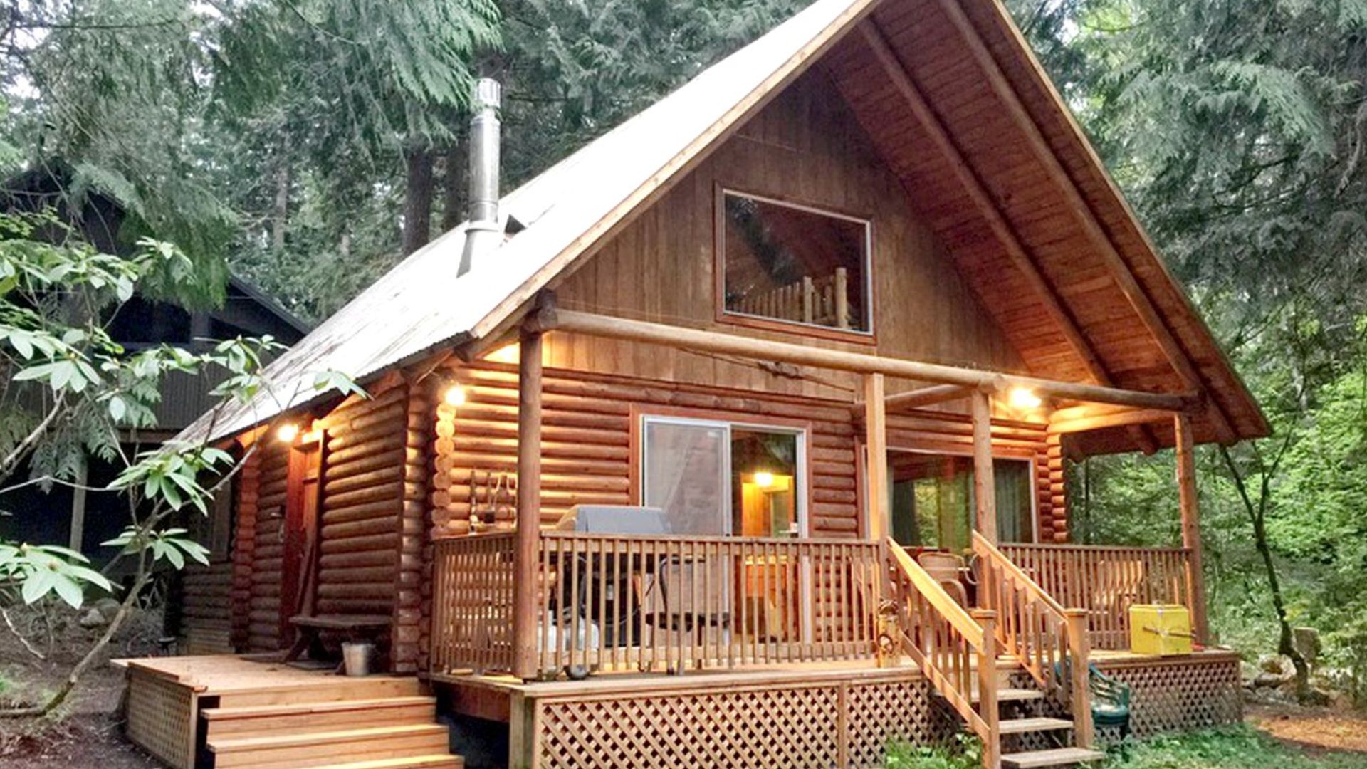 close up photo of the log cabin exterior with a small porch, surrounded by greenery