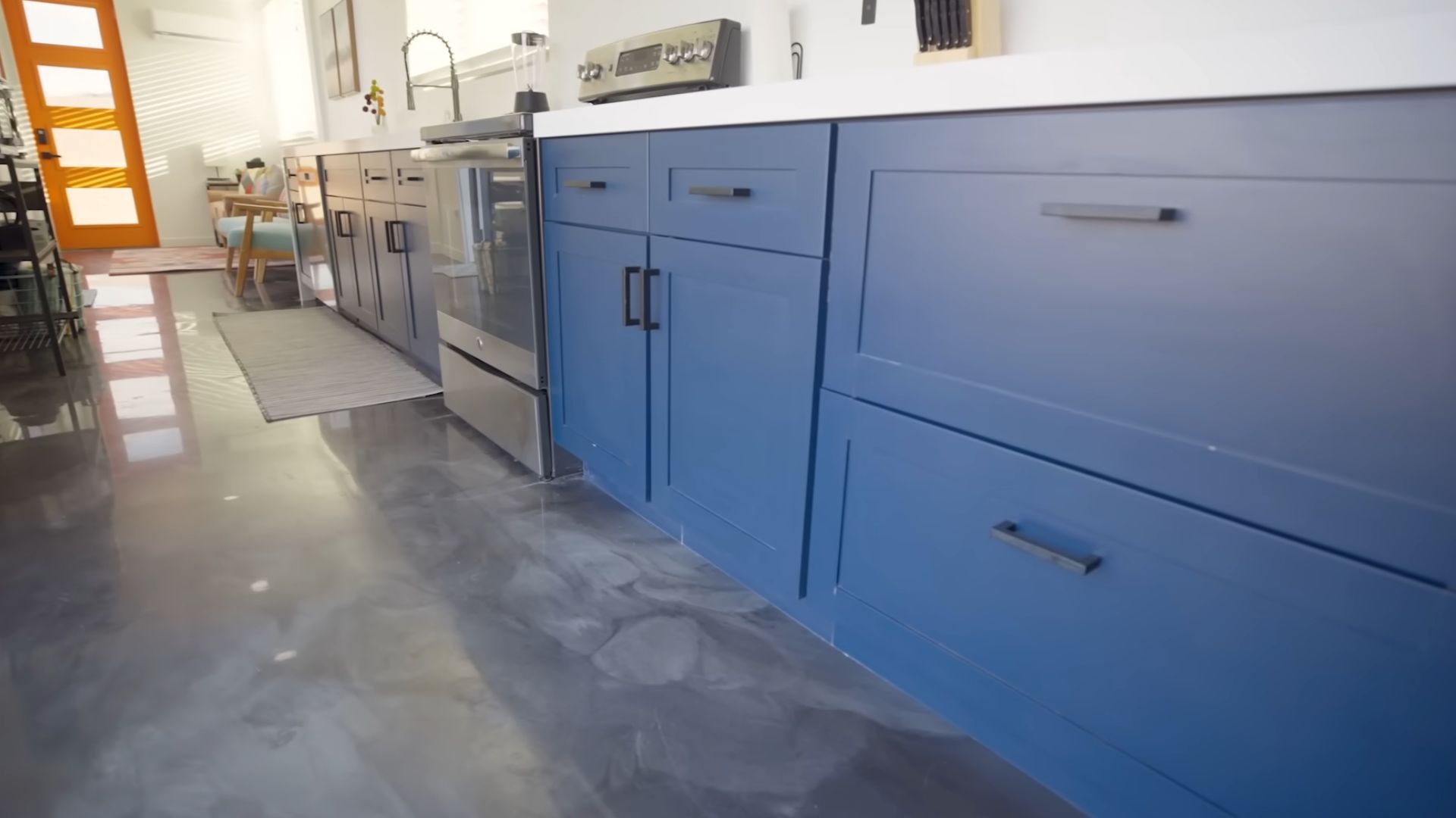 deep blue lower cabinets in the container kitchen and concrete floor with epoxy finish