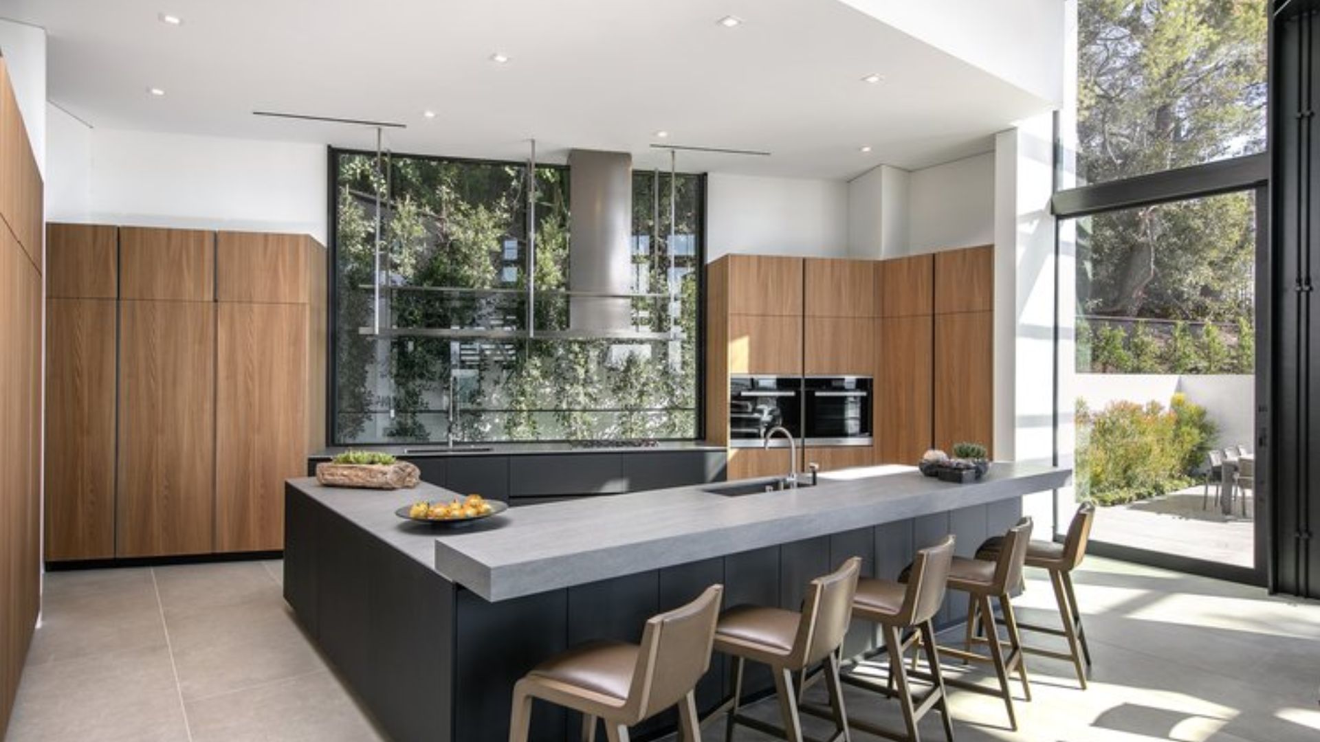 other angle of the kitchen with a massive countertop island and a huge glass wall behind the sink