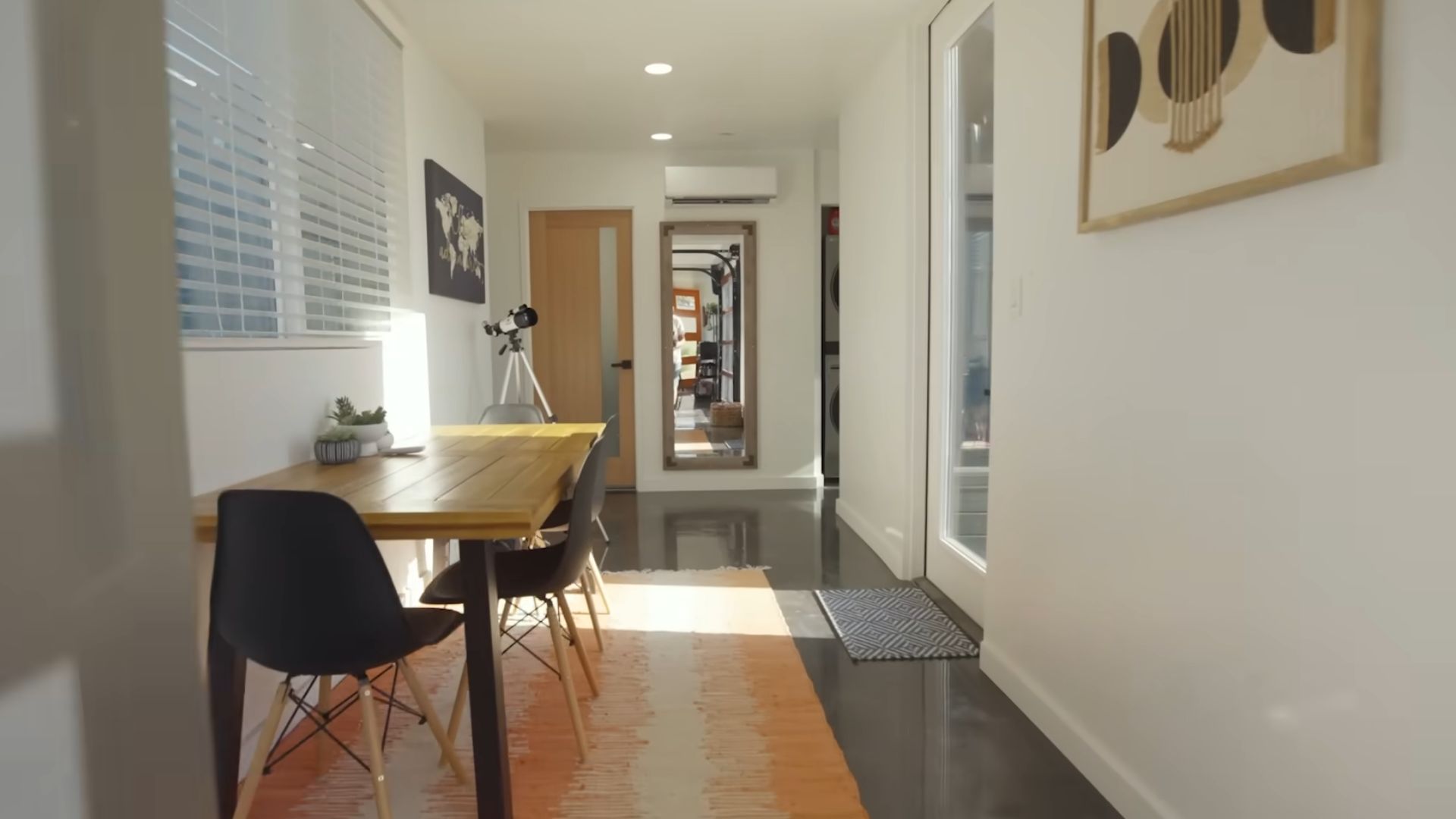 dining table in the hallway of the container home with artwork on the wall