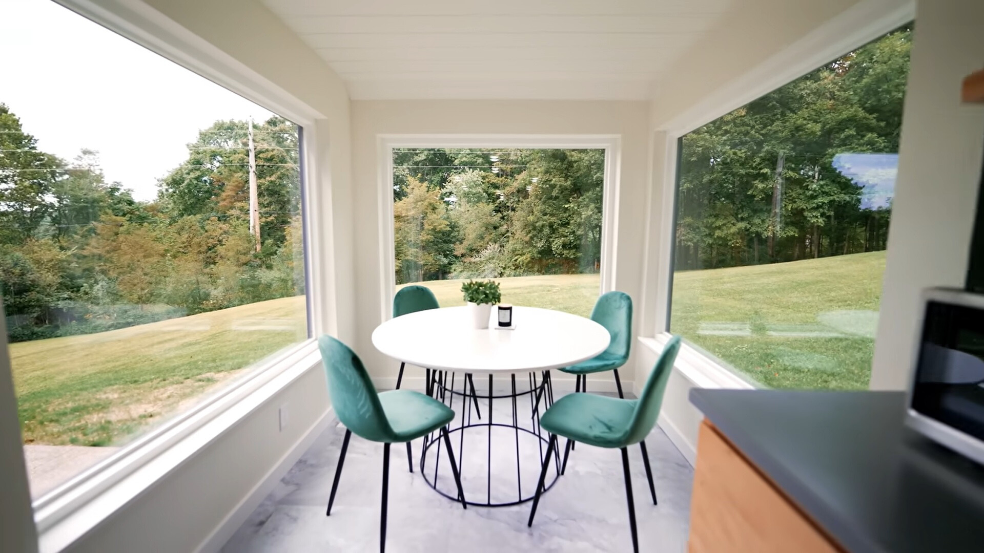 dining area with huge windows all around with a white table and turquoise chairs