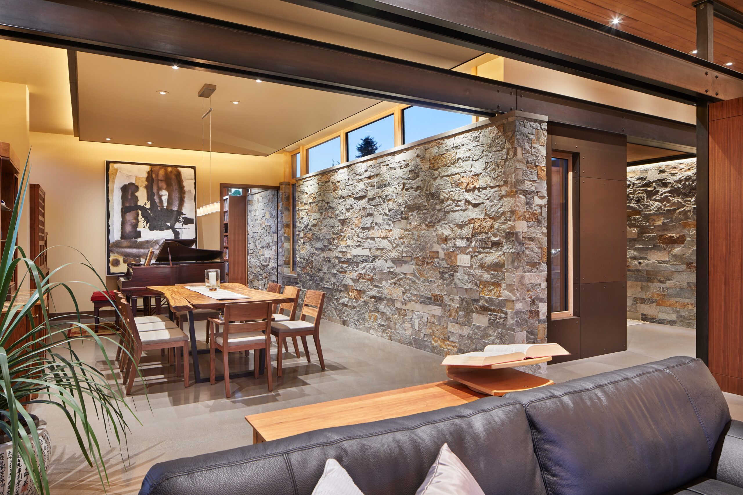 dining room with a wooden dining table and chairs, with one stone wall and a piano