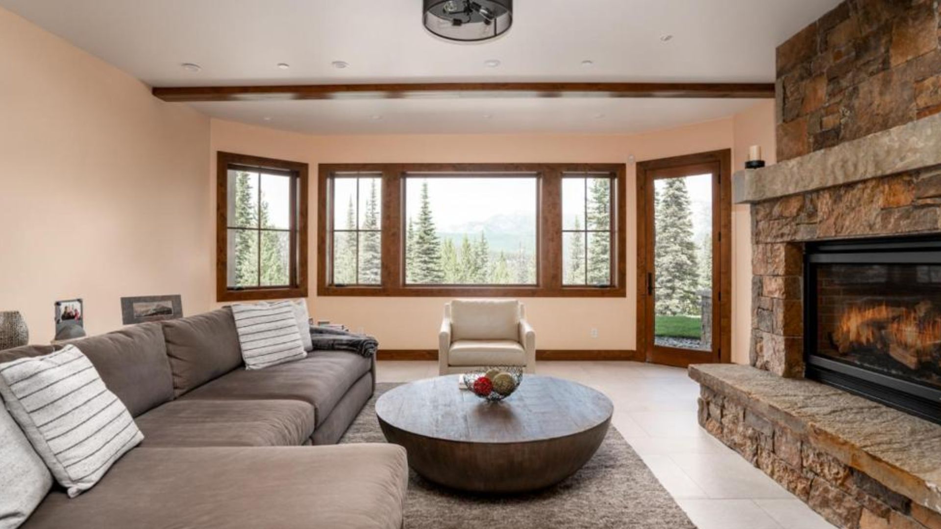 downstairs liing room area with the same big fireplace and grey sofa with a round table