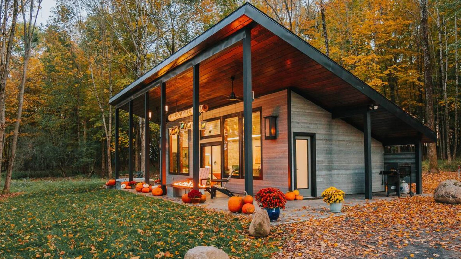 side photo of the tiny house in fall covered in orange leaves and pumpkins