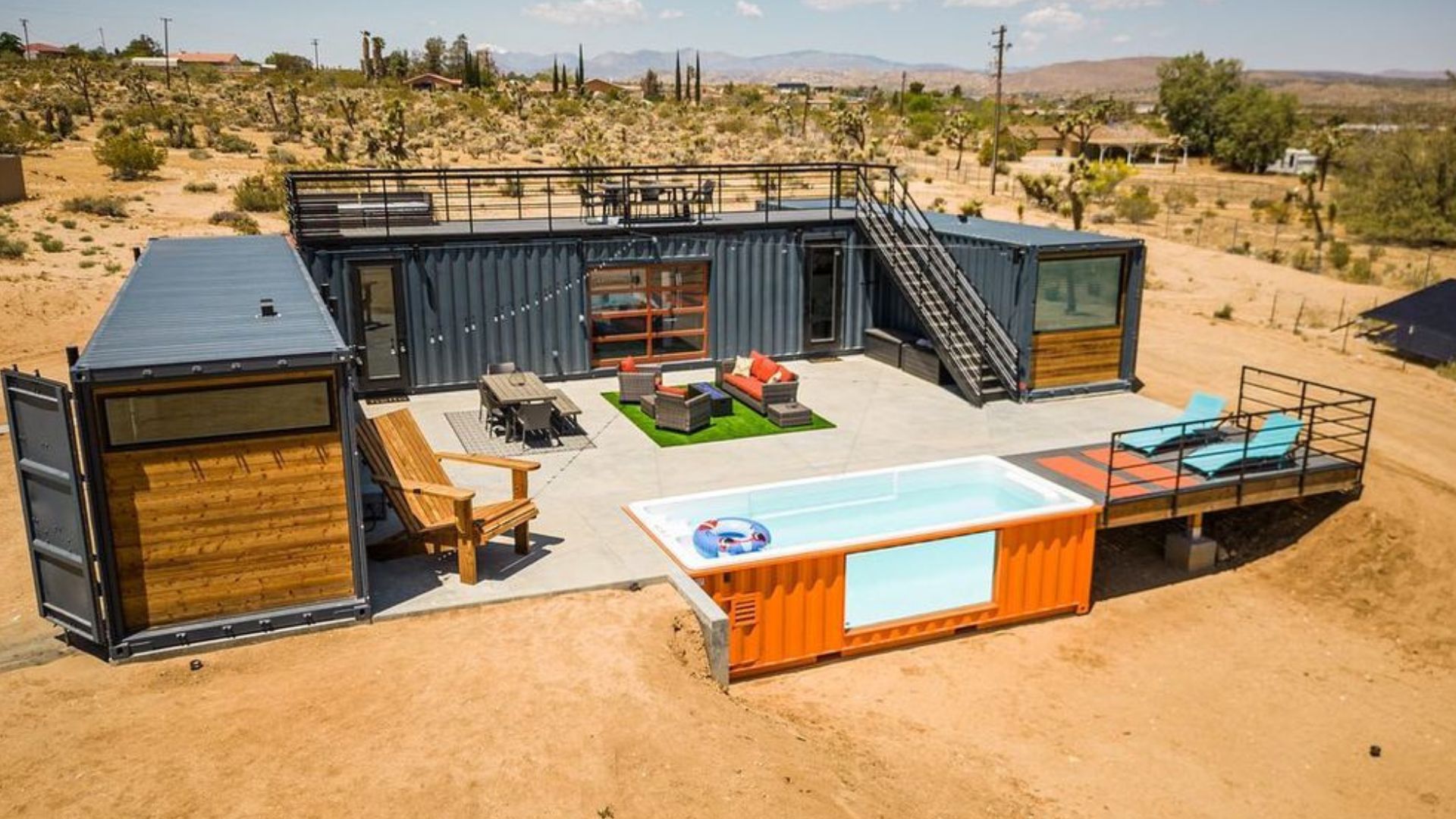 exterior of the modular container house in anthracite with orange details, a big patio, and a cool swimming pool