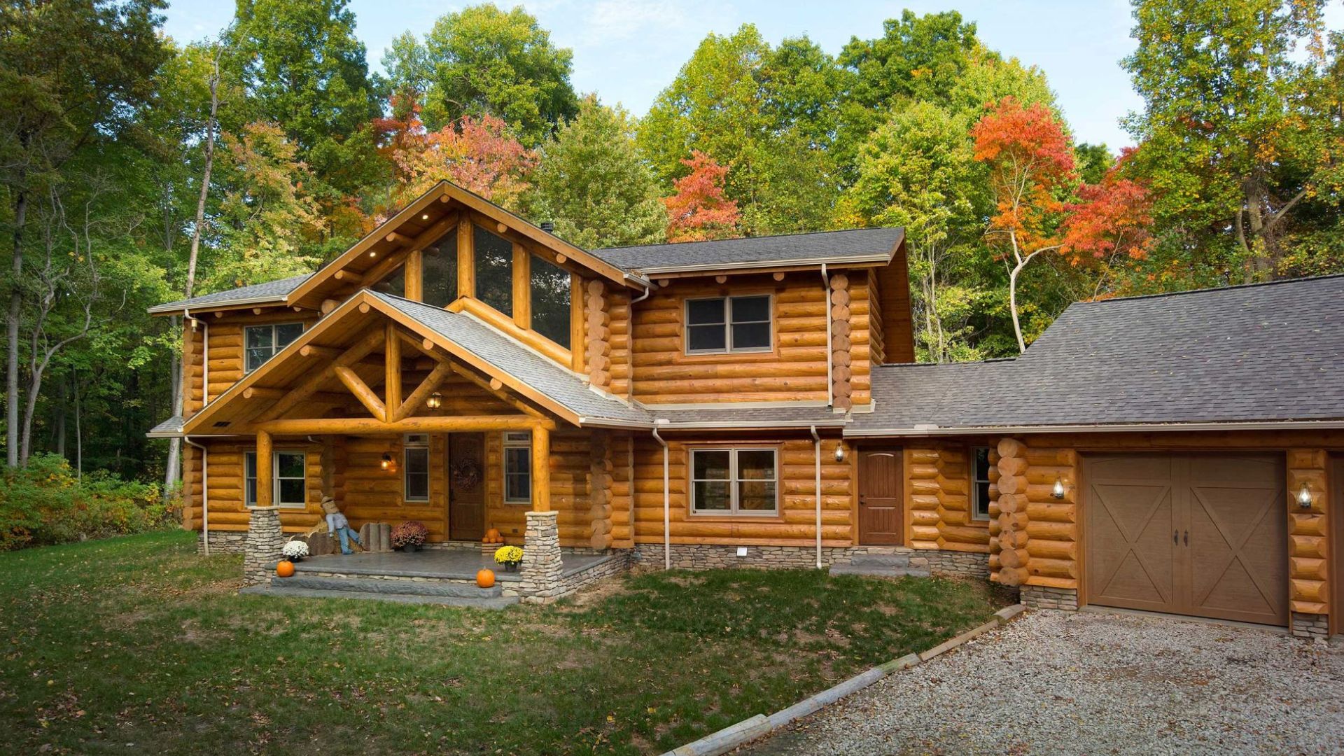 exterior of the log cabin with a lot of windows and a garage adjacent, surrounded by trees