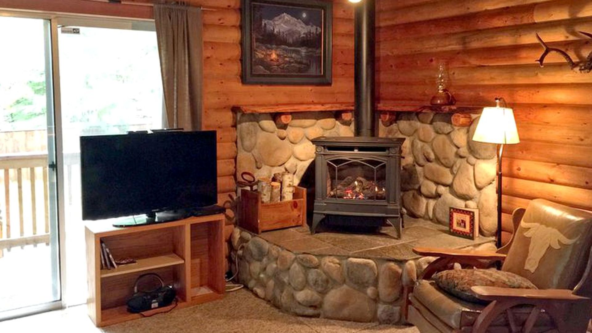 fireplace area with accent stone walls, an armchair next to it, and a TV