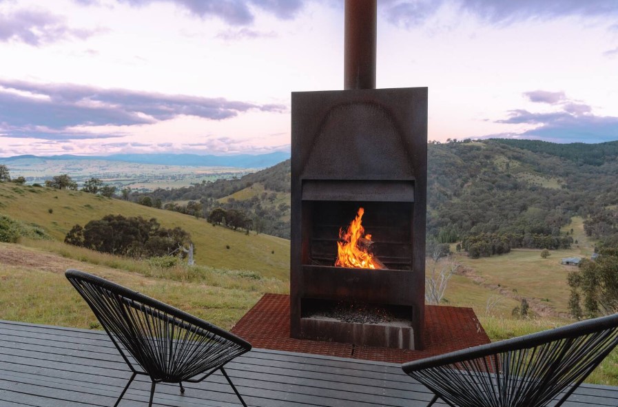 black fireplace outside and two black chairs in front of it