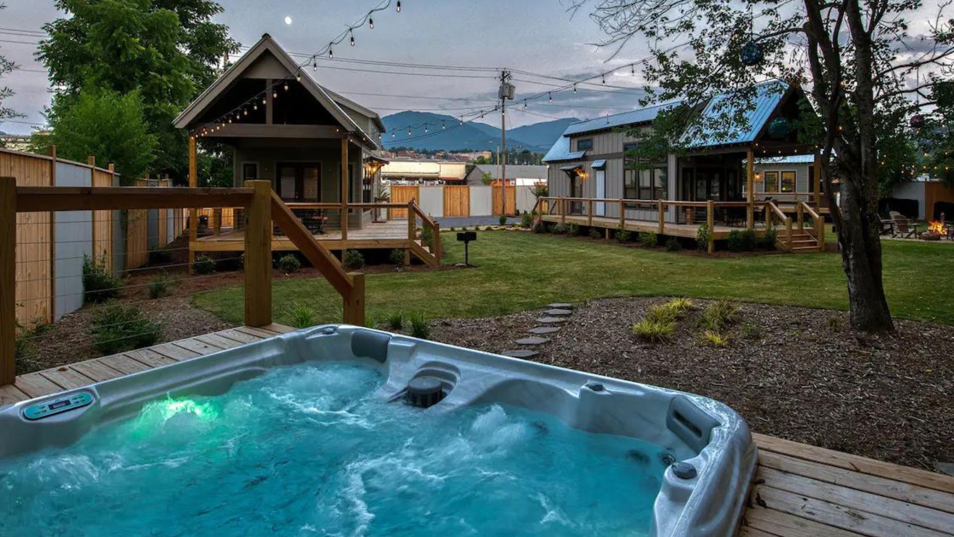 hot tub full of water overlooking the three tiny houses, photo as night falls