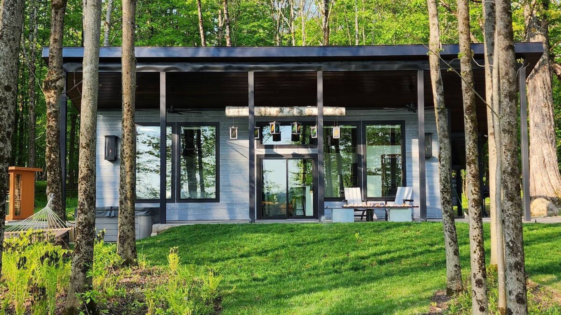 tiny house in grey surrounded by green trees and a beautiful green grass