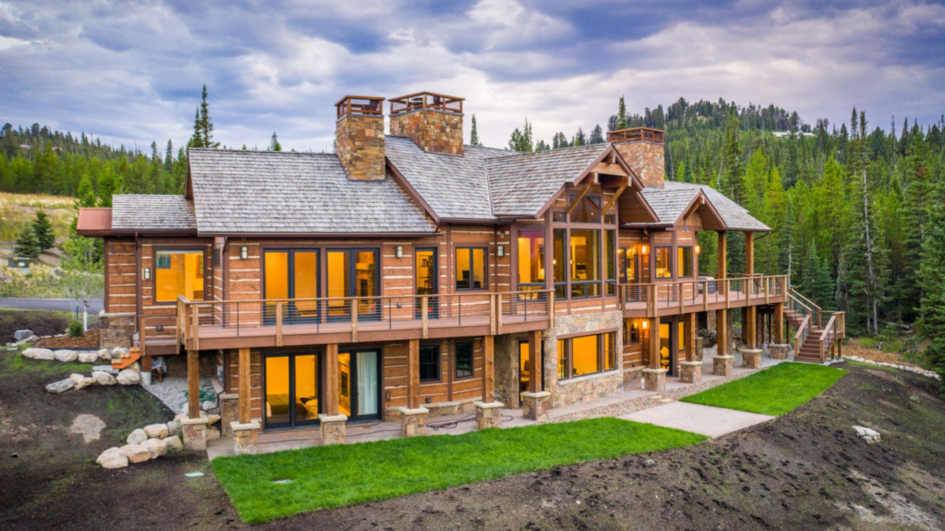 impressive mountain cabin on three levels with lots of windows surrounded by pine trees