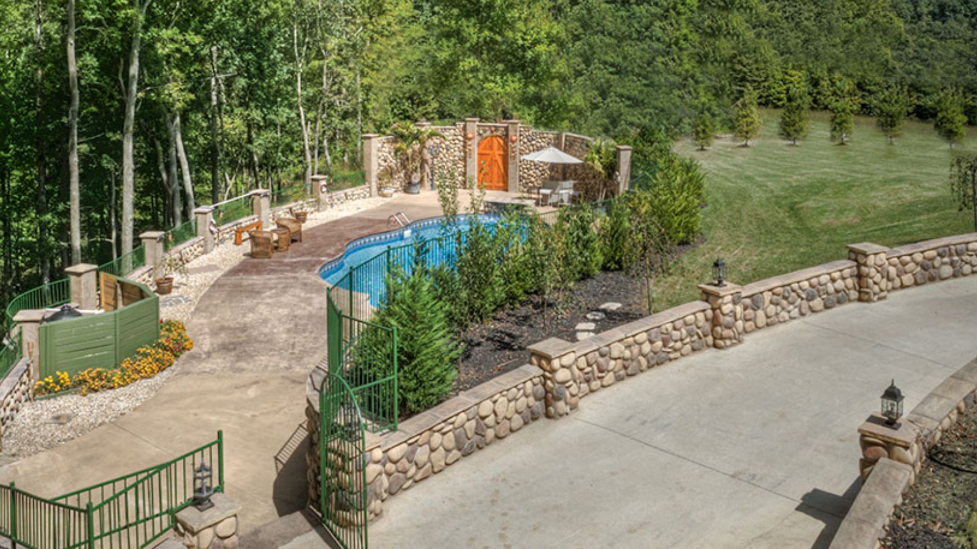 in-ground pool in the garden in a secluded place, stone fence around it and lots of greenery