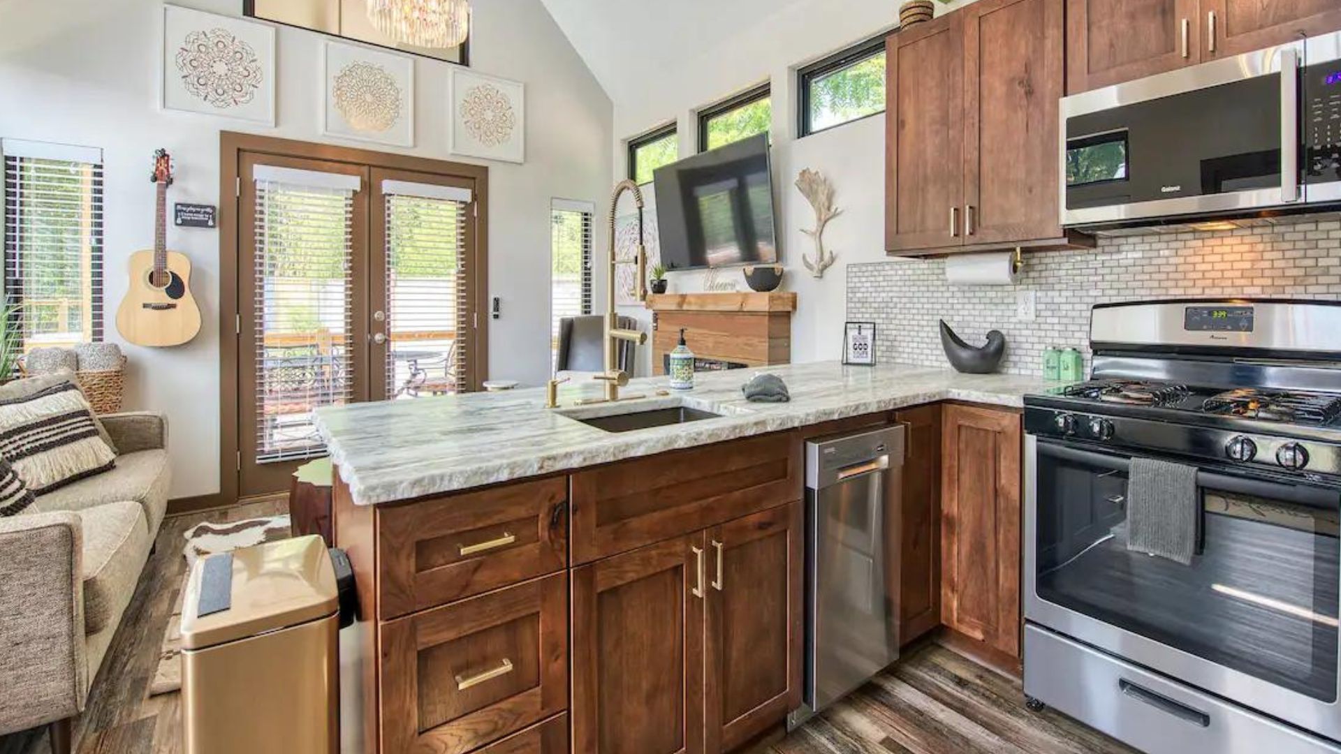 inside the wooden kitchen with stainless steel appliances, overlooking the living room area with lots of natural light