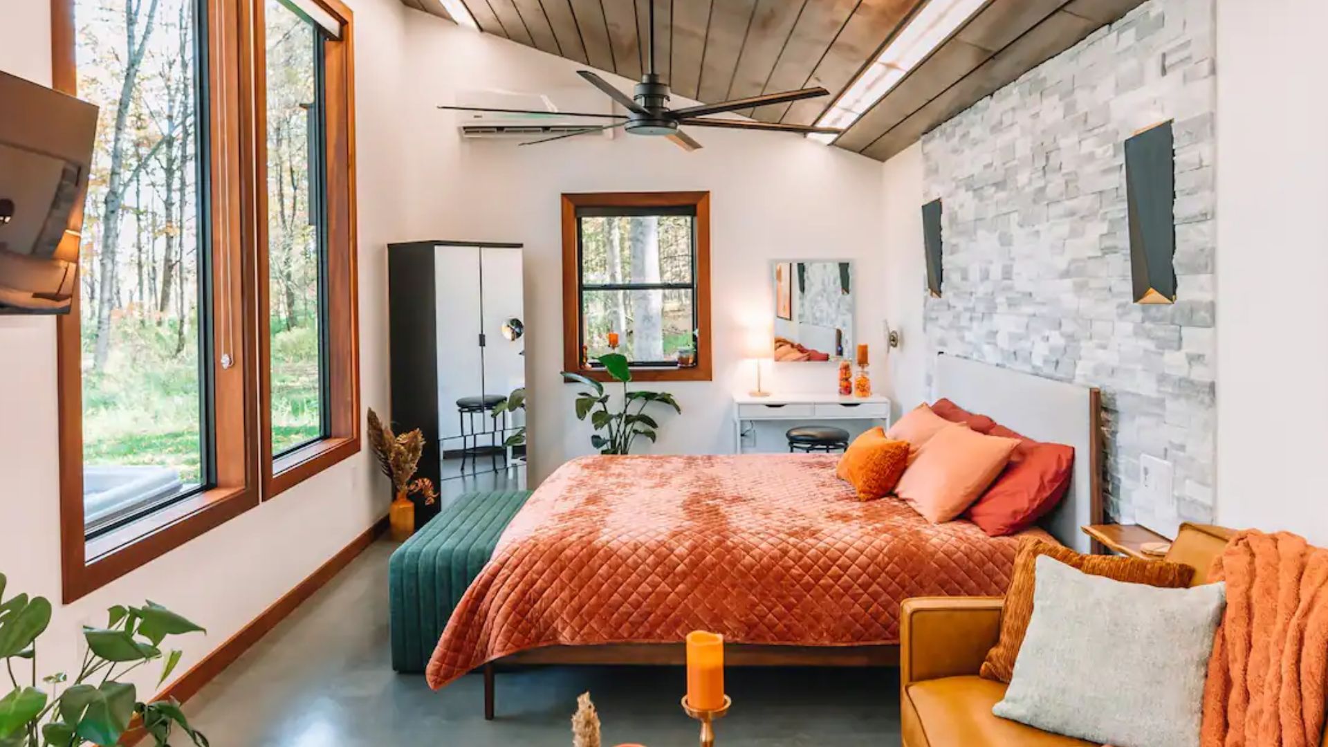 king size bed with a rusty orange blanket facing large picture windows