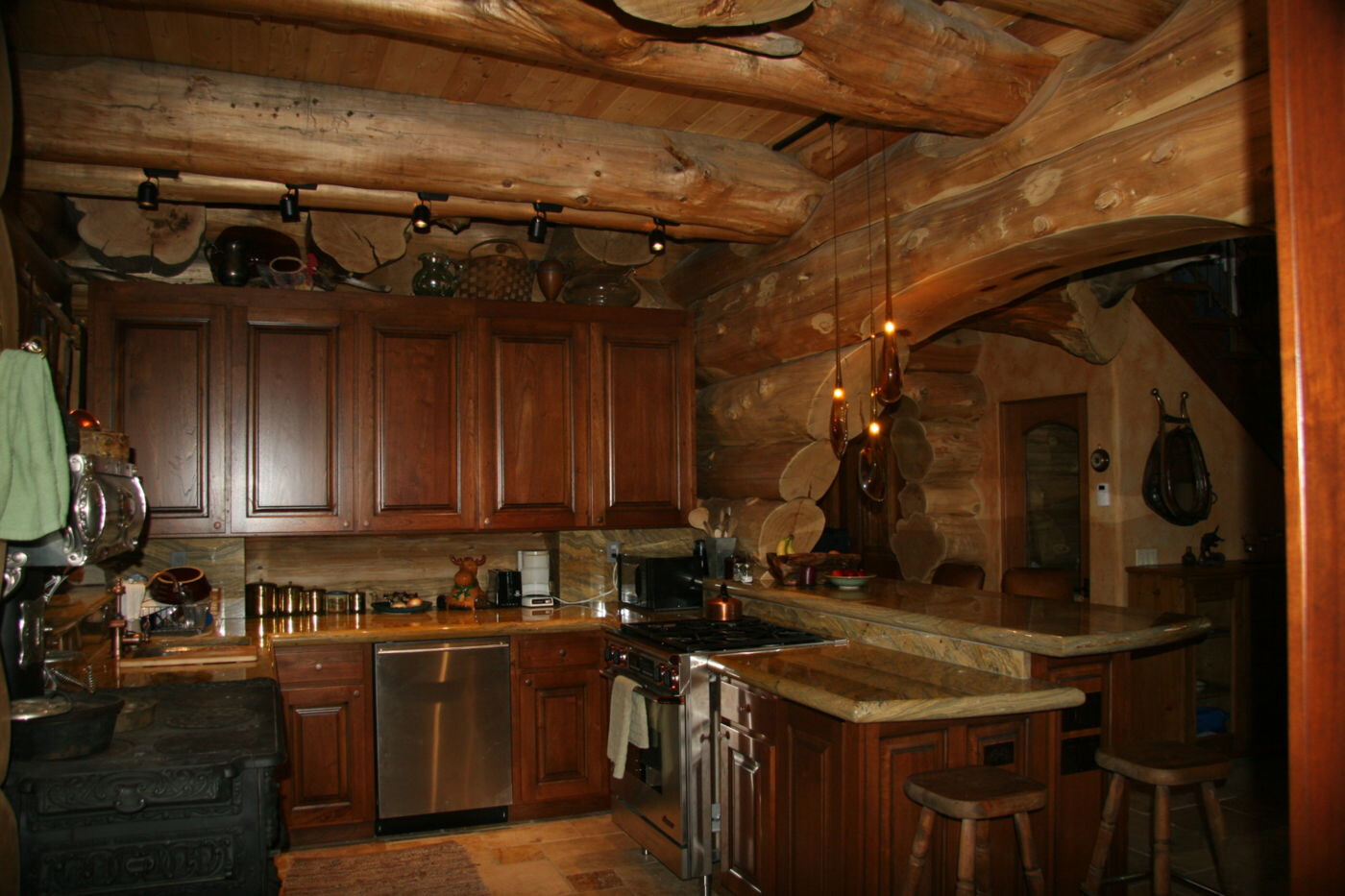 kitchen of a cabin with brown cabinets and a big countertop with brown bar stools