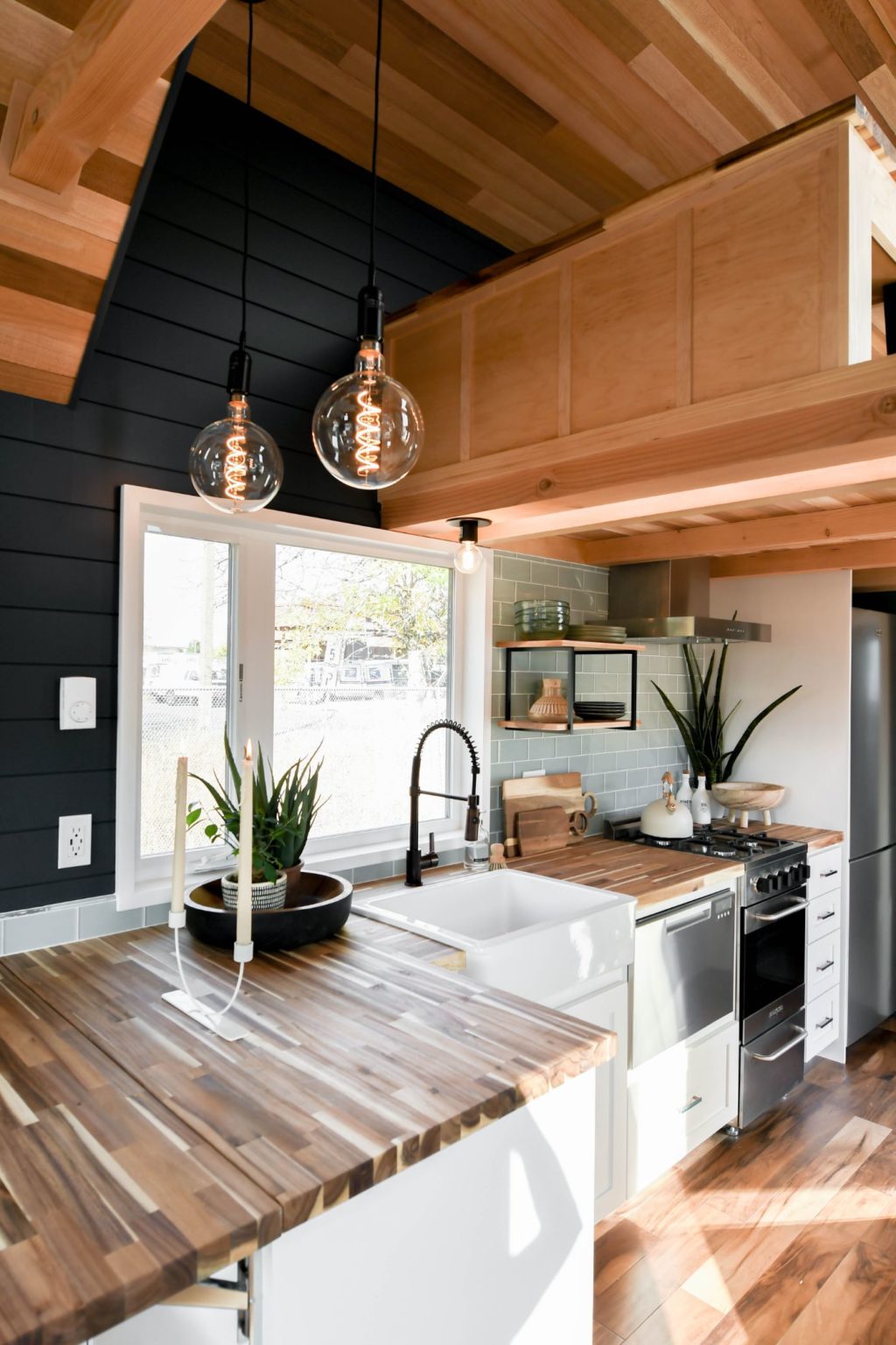 kitchen with a brown countertop, dark walls and a window above the white sink