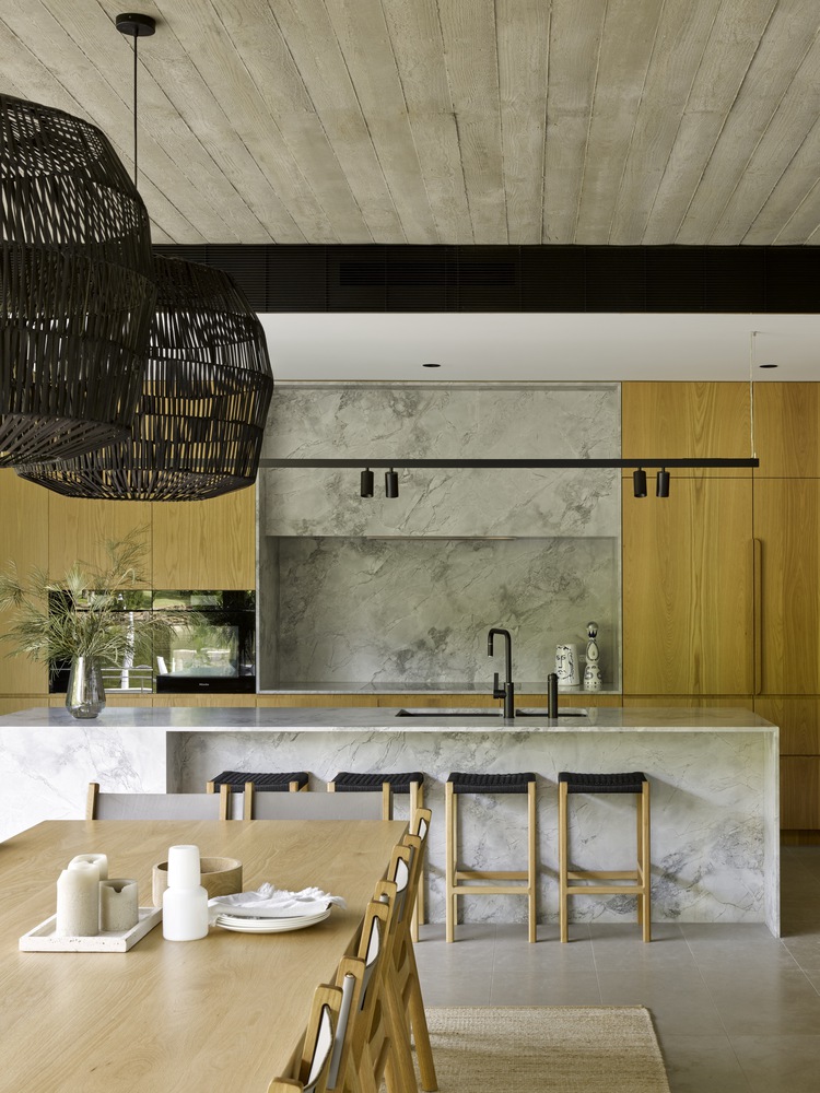 kitchen with brown cabinets and a marble island with stools, brown dining table with chairs around it