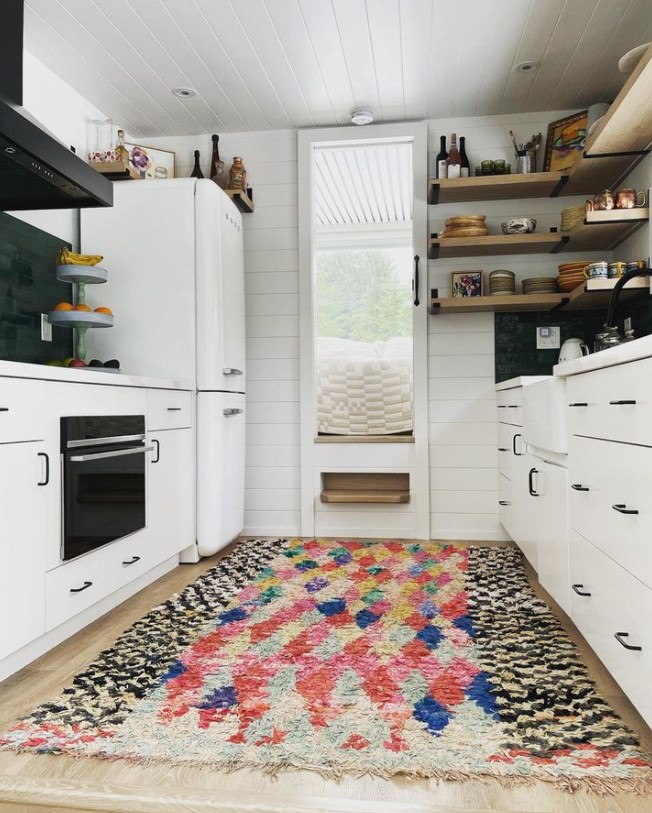 kitchen with white cabinets, brown shelves, colorful carpet