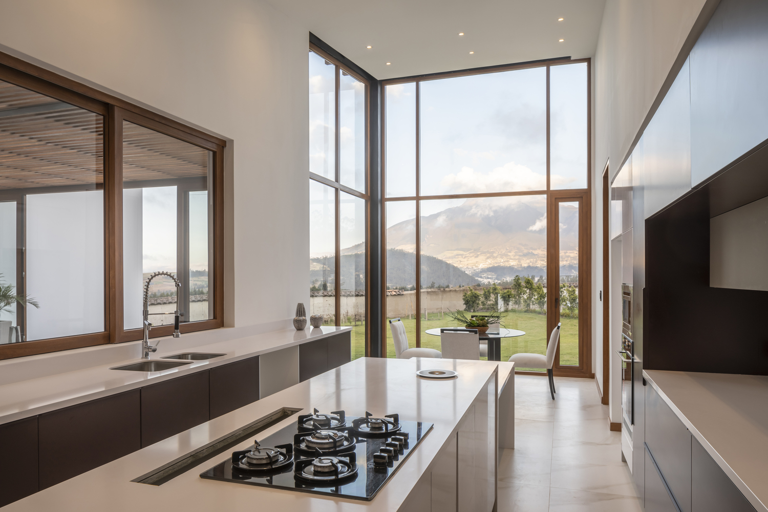 kitchen and dining room with floor to ceiling windows and white countertops, round dining table surrounded by white chairs