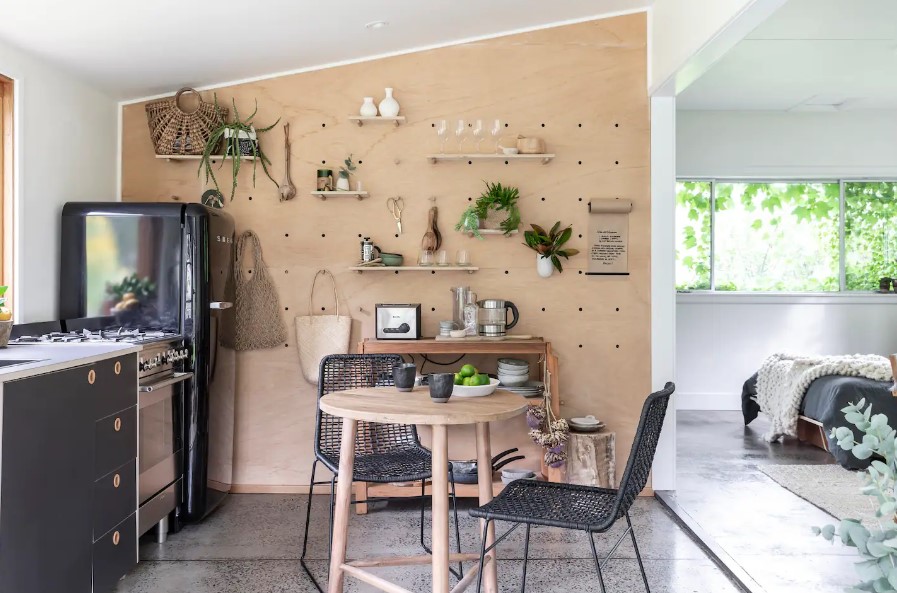 kitchen with black cabinets, shelves with amenities, round dining table with two black chairs