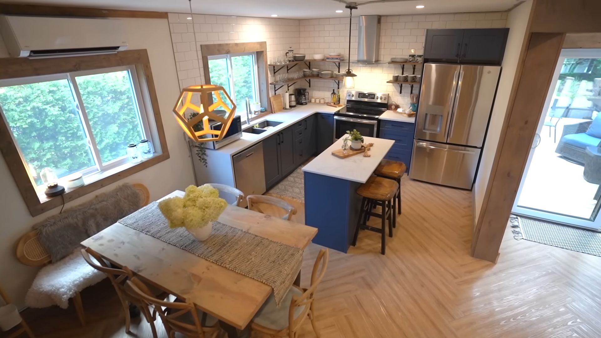 kitchen with cobalt blue cabinets, stainless steel appliances and a dining room area in light wood