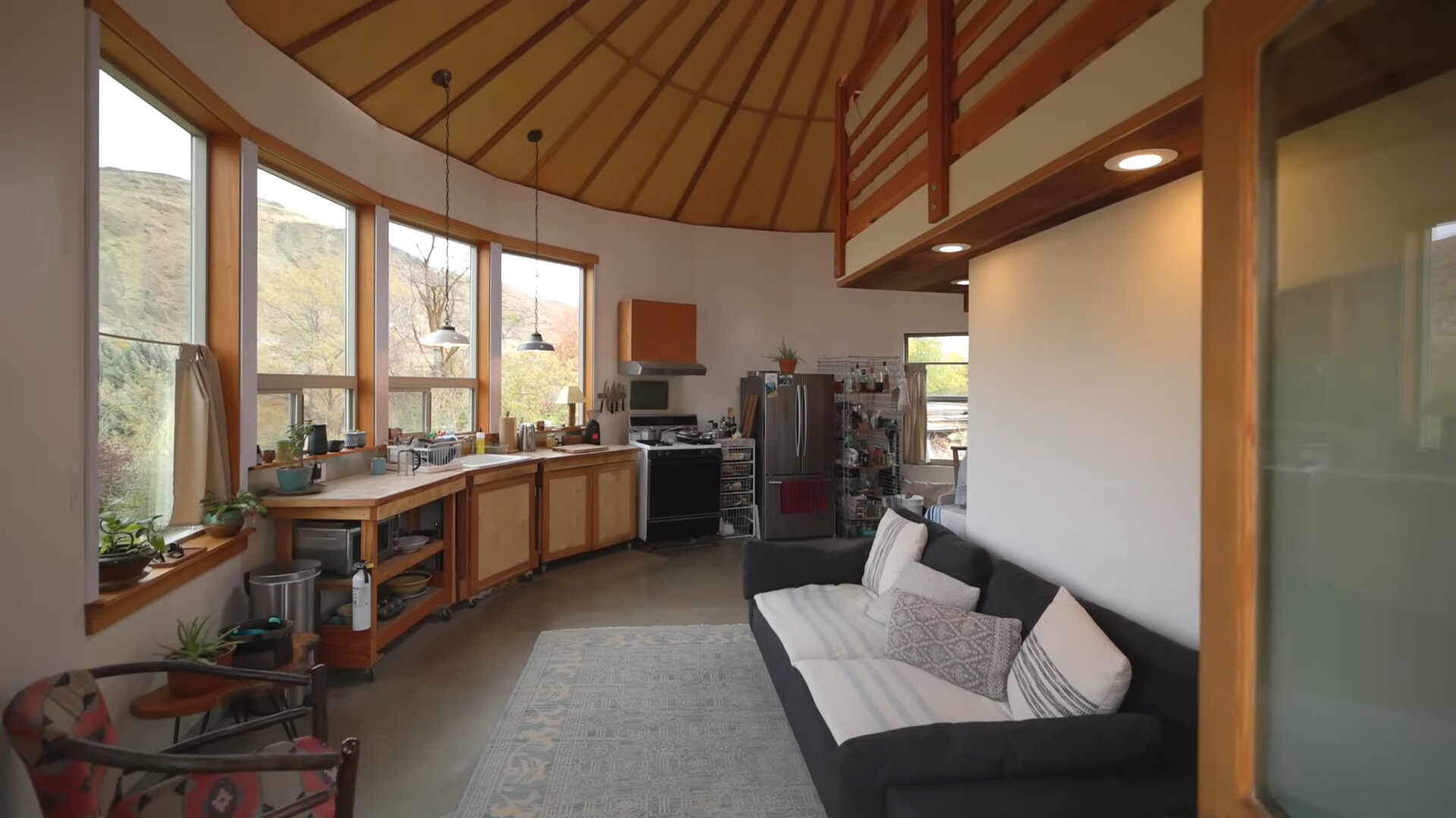 living room and kitchen with a black couch, brown cabinets and big windows