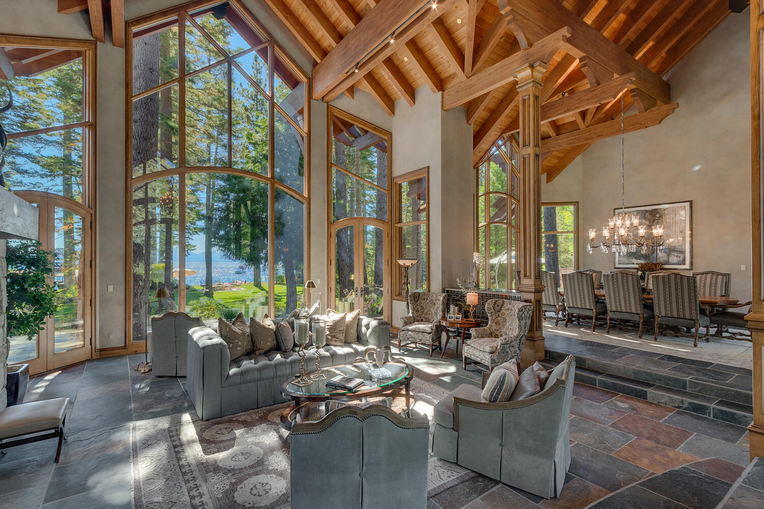 living room and dining room with floor to ceiling windows, turquoise chairs and a couch, oval glass table, long dining table