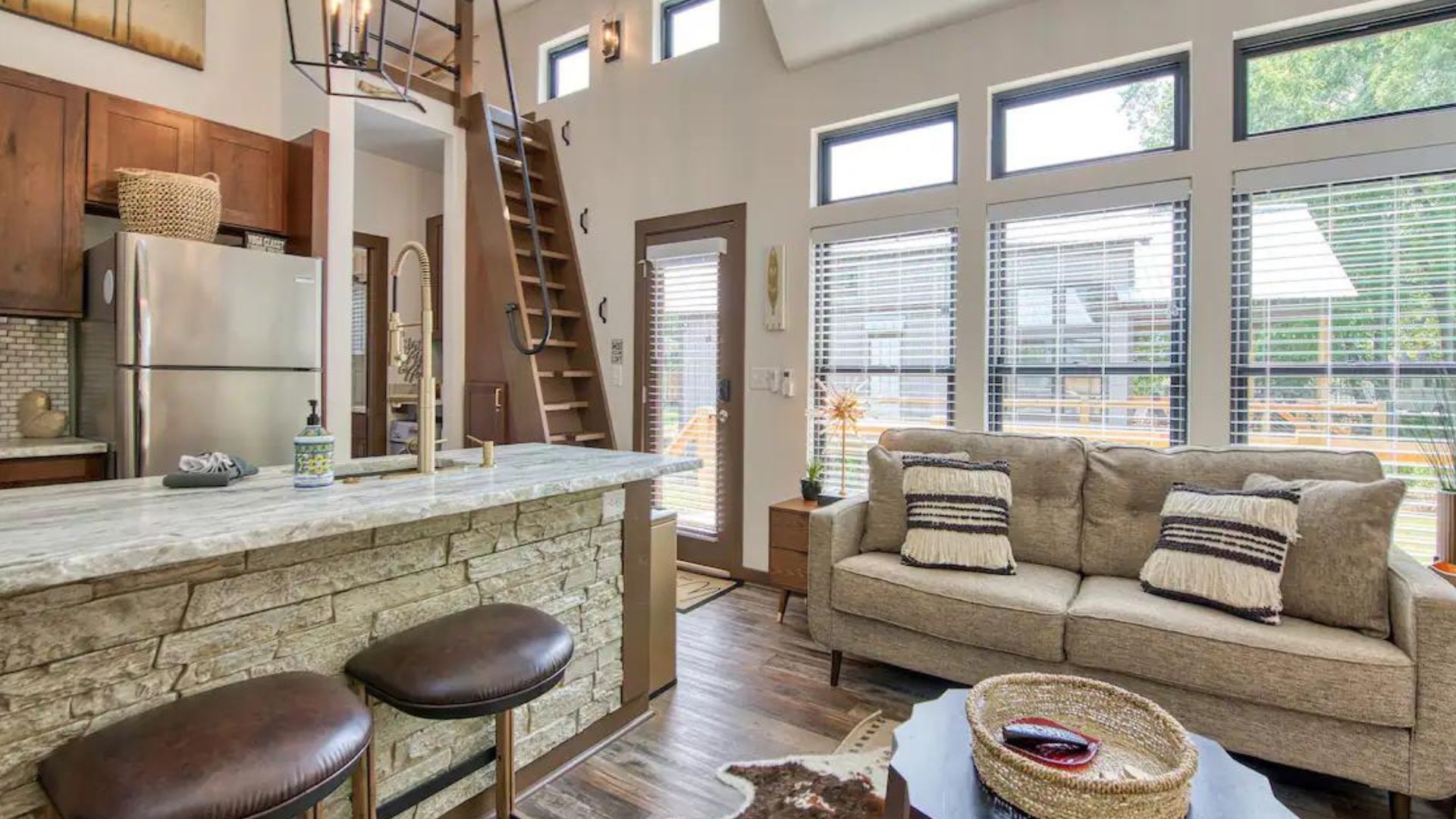 living room area in tiny house with a beige sofa, beige details, cow's skin rug, and a stone bar/ island