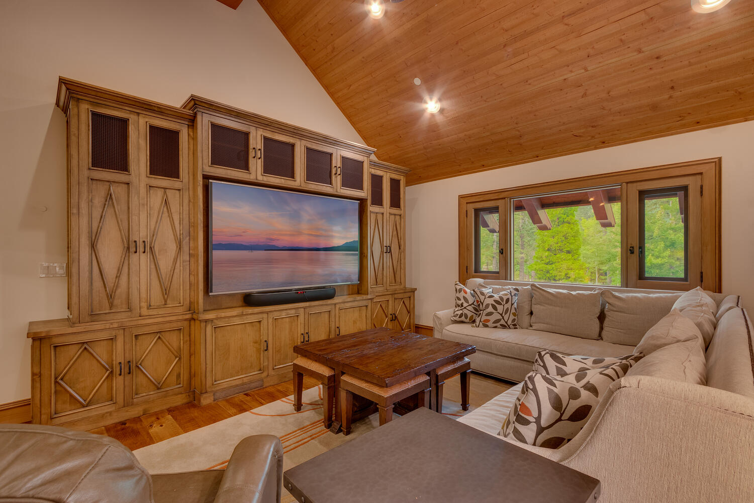 living room with the l-shaped couch, brown cabinet, brown table and flat screen tv