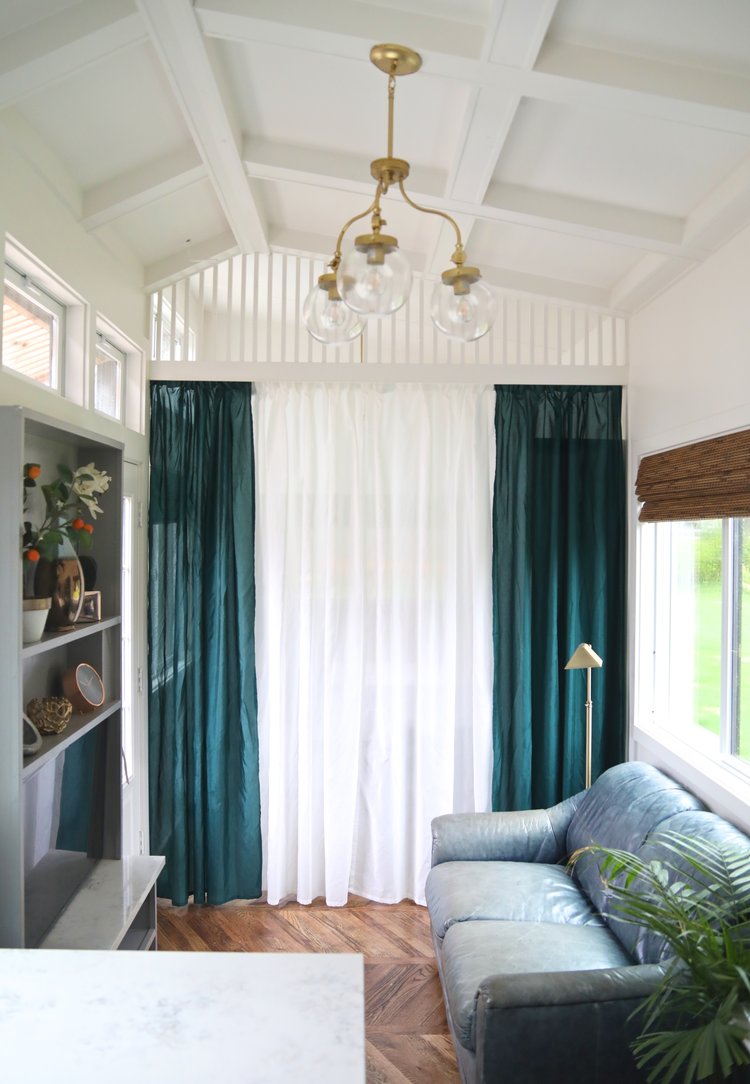 blue couch, gray shelf with decor, chandelier and blue and white curtains