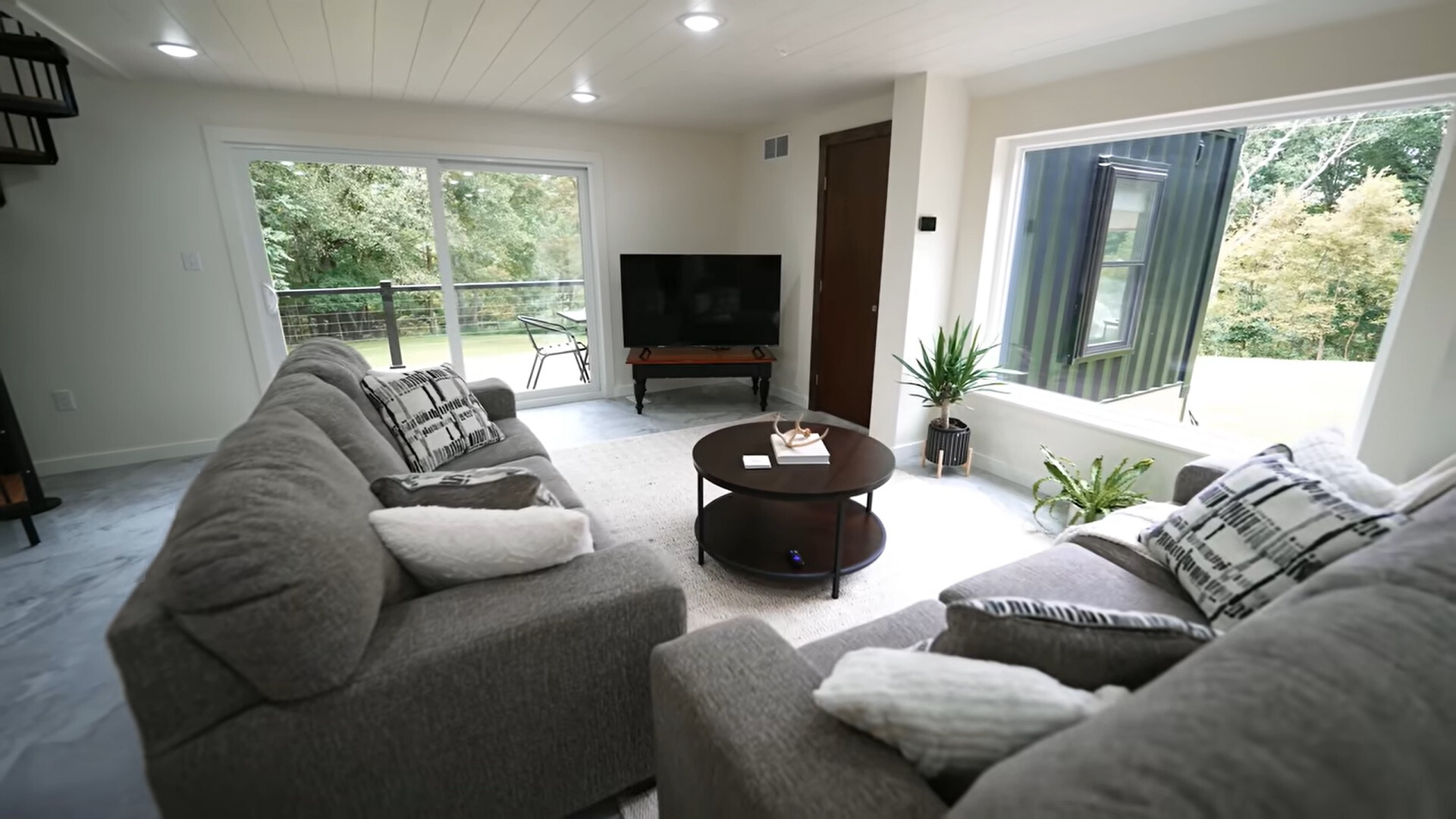 living room with gray couches and big windows and a flat screen tv