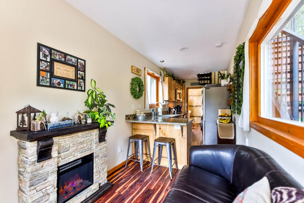 living room with a black couch, brown parquet, a fireplace and plants