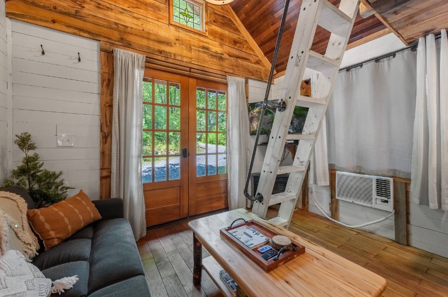 living room of a cabin with a dark gray couch, wooden table and a flat screen tv