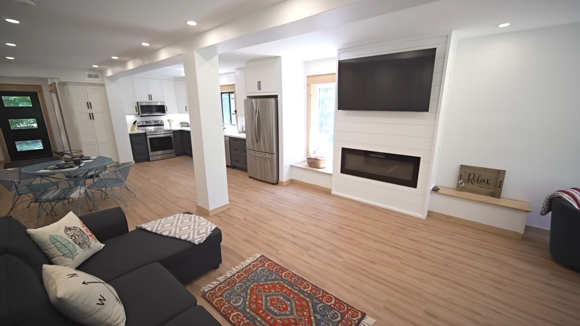 living room with sofa in front of an electric fireplace and a TV above it