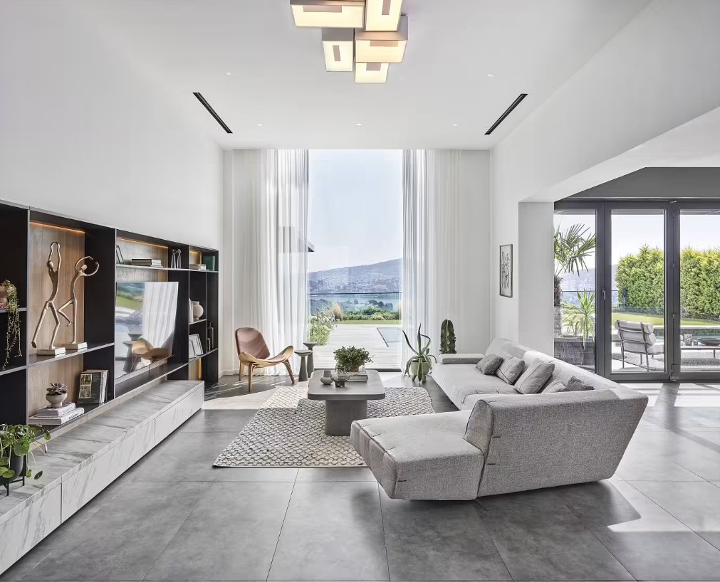 living room with a gray couch, floor to ceiling windows, flat screen tv and a black shelf